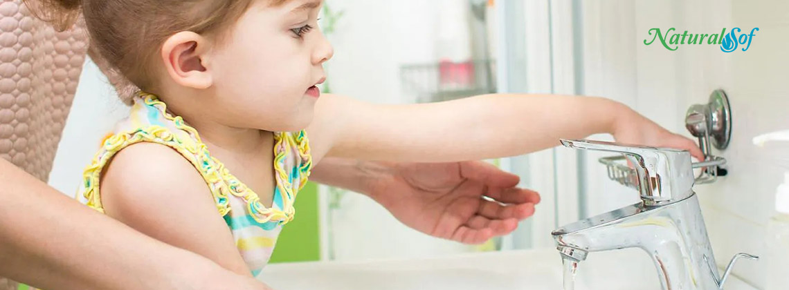 Little girl pouring water from the faucet